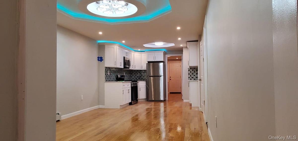 Kitchen featuring backsplash, white cabinetry, appliances with stainless steel finishes, light wood-style floors, and light countertops