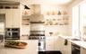 Kitchen with open shelves, wall chimney range hood, high end appliances, light stone counters, and modern cabinets
