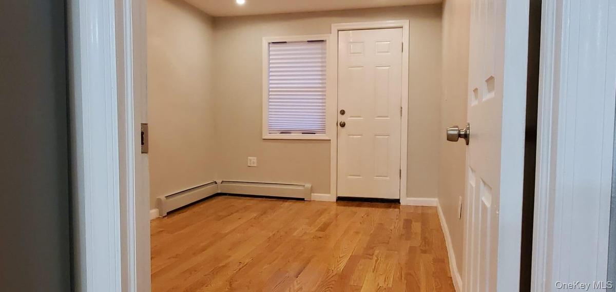 Doorway with wood finished floors, a baseboard heating unit, and recessed lighting