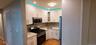 Kitchen with appliances with stainless steel finishes, white cabinets, light stone counters, glass insert cabinets, and light wood finished floors