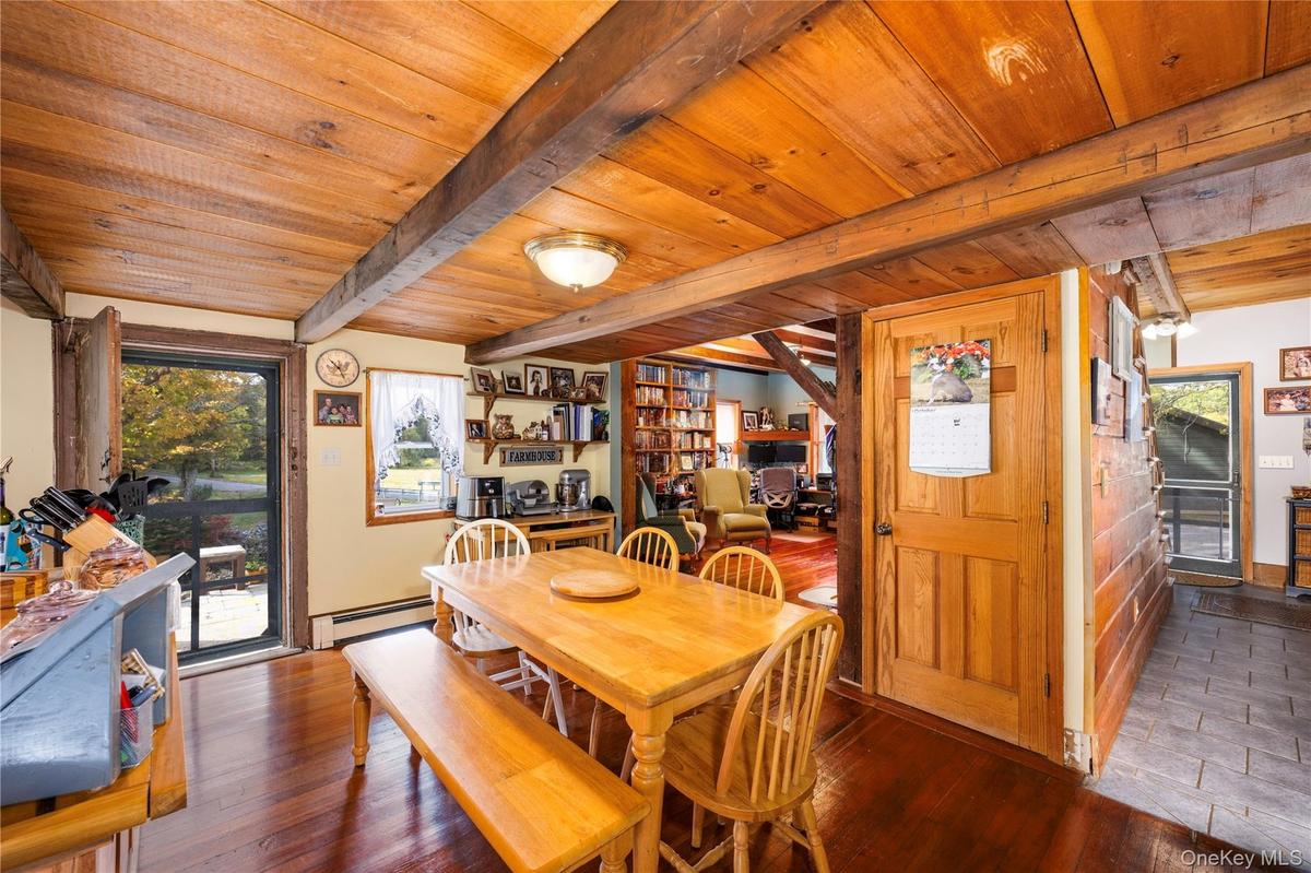 Dining area featuring hardwood / wood-style floors, baseboard heating, and a wooden ceiling with exposed beams