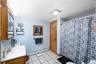 Bathroom featuring baseboard heating, light tile patterned floors, vanity, and a shower with shower curtain