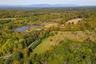 Aerial overview of property's location with a forest and a nearby body of water