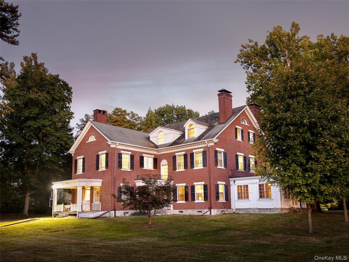 Back of property featuring a chimney, brick siding, and a lawn