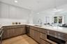 Kitchen with white cabinetry, sink, dishwasher, pendant lighting, and light wood-type flooring
