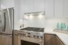 Kitchen featuring white cabinets, backsplash, stainless steel appliances, and extractor fan