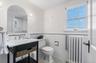 Bathroom featuring radiator, tile walls, a wainscoted wall, light tile patterned flooring, and vanity