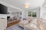 Living area with wood finished floors, a fireplace with flush hearth, and radiator