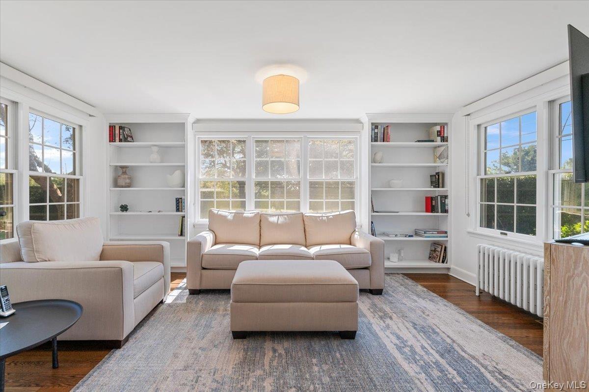 Sitting room featuring wood finished floors, radiator, and built in shelves