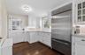 Kitchen with decorative backsplash, stainless steel built in refrigerator, white cabinets, and dark wood finished floors