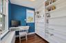 Home office with dark wood-style flooring and radiator