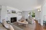 Living room with wood finished floors, a fireplace with flush hearth, and french doors