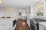 Kitchen with built in appliances, white cabinetry, glass insert cabinets, dark wood-style floors, and tasteful backsplash