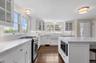 Kitchen with glass insert cabinets, appliances with stainless steel finishes, white cabinetry, and a breakfast bar area