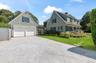 View of front of house featuring driveway, a front lawn, a chimney, and an attached garage