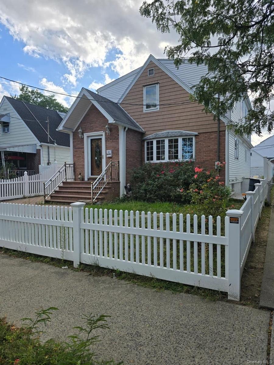View of front facade with brick siding and a fenced front yard