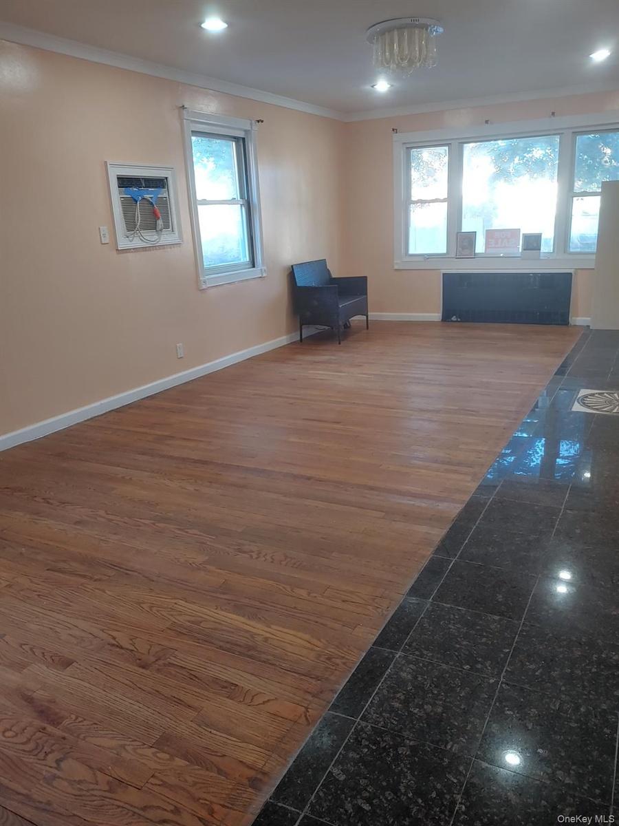 Living room with crown molding, dark wood-type flooring, and radiator heating unit