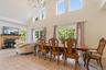 Tiled dining room with an inviting chandelier, a brick fireplace, a healthy amount of sunlight, and a towering ceiling