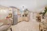 Kitchen with decorative light fixtures, stainless steel refrigerator, cream cabinetry, and light tile patterned flooring