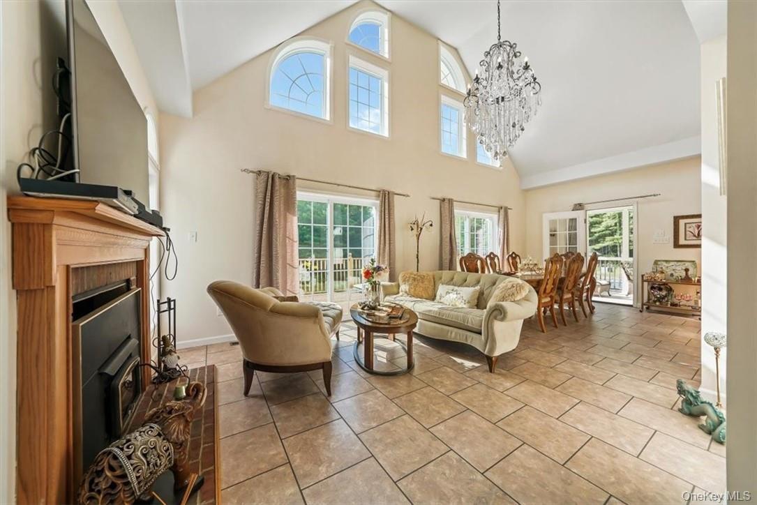 Tiled living room with an inviting chandelier, a healthy amount of sunlight, and high vaulted ceiling
