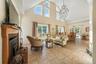 Tiled living room with an inviting chandelier, a healthy amount of sunlight, and high vaulted ceiling