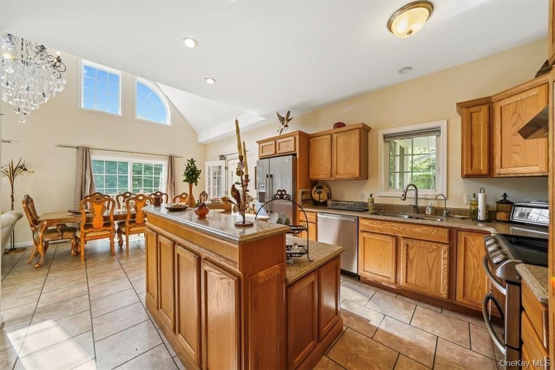 Kitchen featuring appliances with stainless steel finishes, a healthy amount of sunlight, light tile patterned floors, and a kitchen island