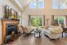 Tiled living room with a brick fireplace, high vaulted ceiling, and an inviting chandelier