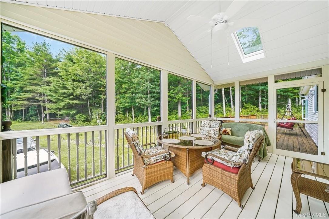 Sunroom / solarium with vaulted ceiling with skylight and ceiling fan