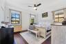Spacious primary bedroom with large windows, ample natural light, and a modern ceiling fan. Features a light wood furniture set and a cozy, inviting a