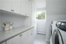 Clothes washing area with a baseboard heating unit, washing machine and clothes dryer, and cabinets