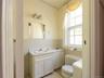 Half bath featuring tile walls, healthy amount of natural light, vanity, radiator heating unit, and wainscoting