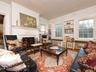 Living room featuring ornamental molding, a warm lit fireplace, and wood finished floors