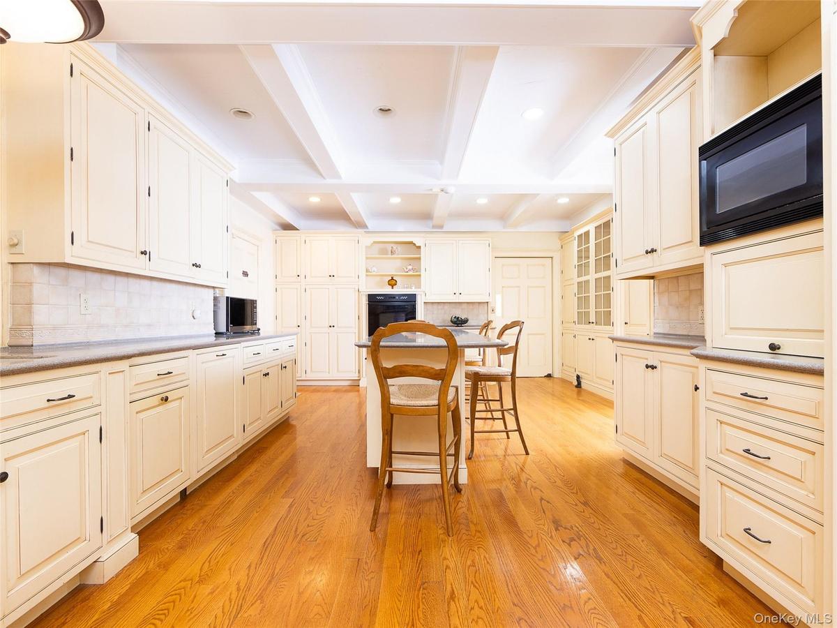 Kitchen with backsplash, open shelves, beamed ceiling, a kitchen bar, and black appliances