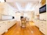 Kitchen with backsplash, open shelves, beamed ceiling, a kitchen bar, and black appliances