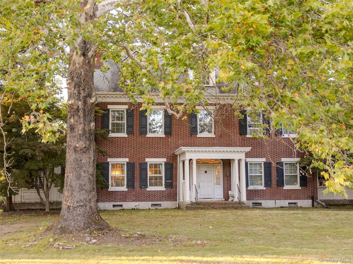 Georgian-style home featuring brick siding, a front lawn, and crawl space