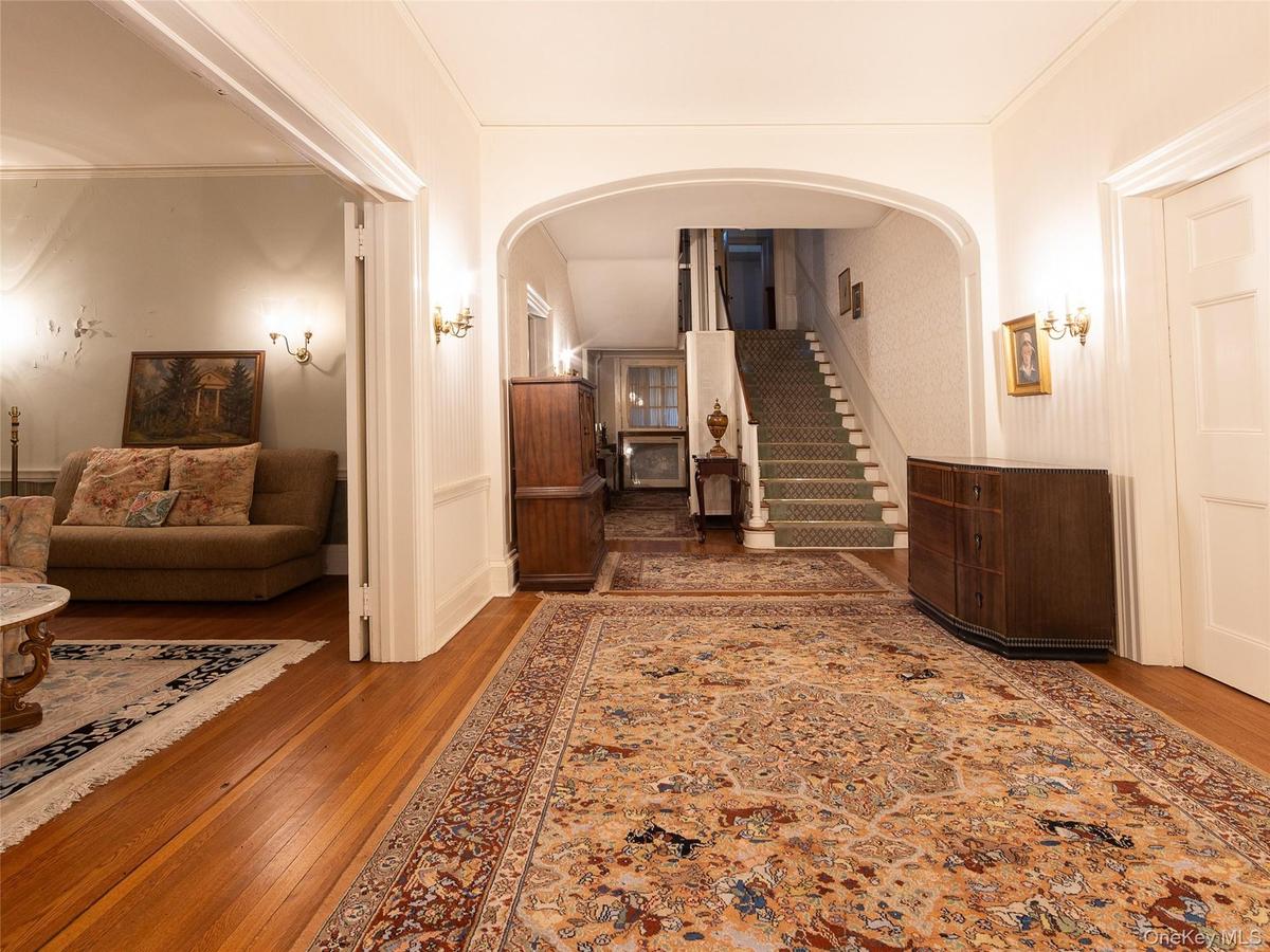 Hall featuring hardwood / wood-style flooring, stairs, arched walkways, and ornamental molding