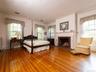 Bedroom featuring crown molding, multiple windows, wood finished floors, and a brick fireplace