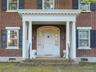 Entrance to property featuring brick siding and covered porch
