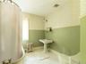 Full bath with radiator, light tile patterned flooring, wallpapered walls, and a wainscoted wall