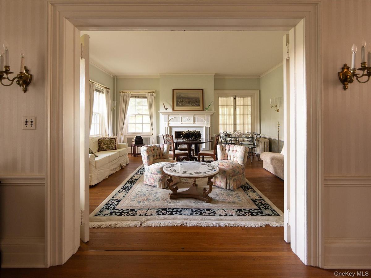 Living room with dark wood-type flooring, a fireplace, and ornamental molding