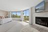 Bedroom featuring access to exterior, a glass covered fireplace, and wood finished floors