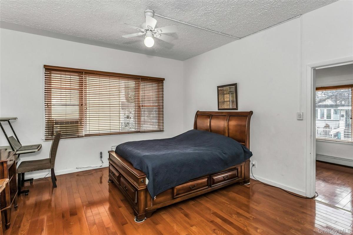 Bedroom featuring dark wood-style floors, a textured ceiling, and a ceiling fan