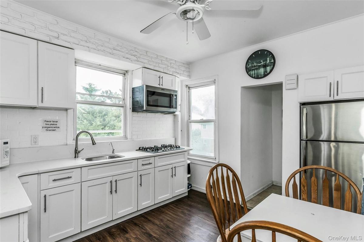 Kitchen with stainless steel appliances, tasteful backsplash, ceiling fan, light countertops, and white cabinetry