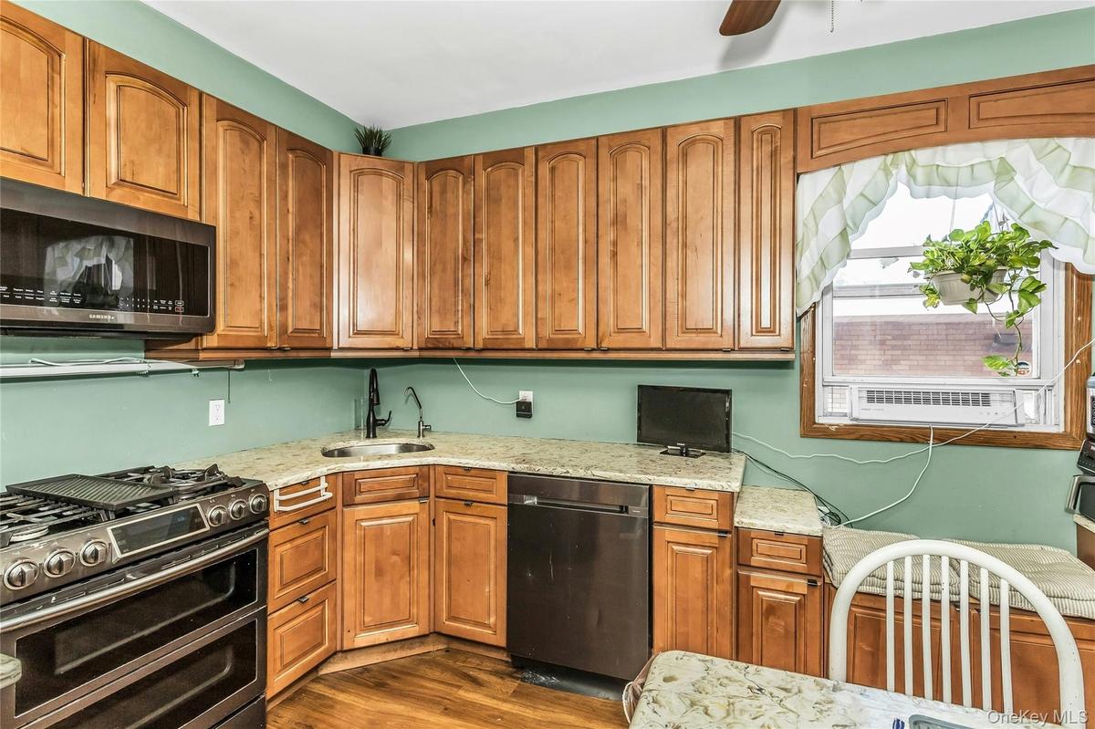 Kitchen featuring double oven range, dishwashing machine, dark wood-style floors, light stone countertops, and a ceiling fan
