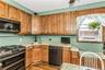 Kitchen featuring double oven range, dishwashing machine, dark wood-style floors, light stone countertops, and a ceiling fan