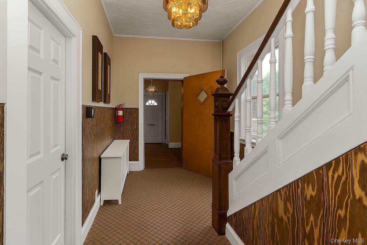 Foyer with a chandelier, carpet floors, and wood walls
