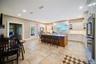Kitchen featuring glass insert cabinets, stainless steel appliances, white cabinets, backsplash, and a kitchen breakfast bar
