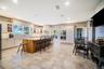 Kitchen with glass insert cabinets, white cabinets, light stone countertops, brown cabinetry, and recessed lighting
