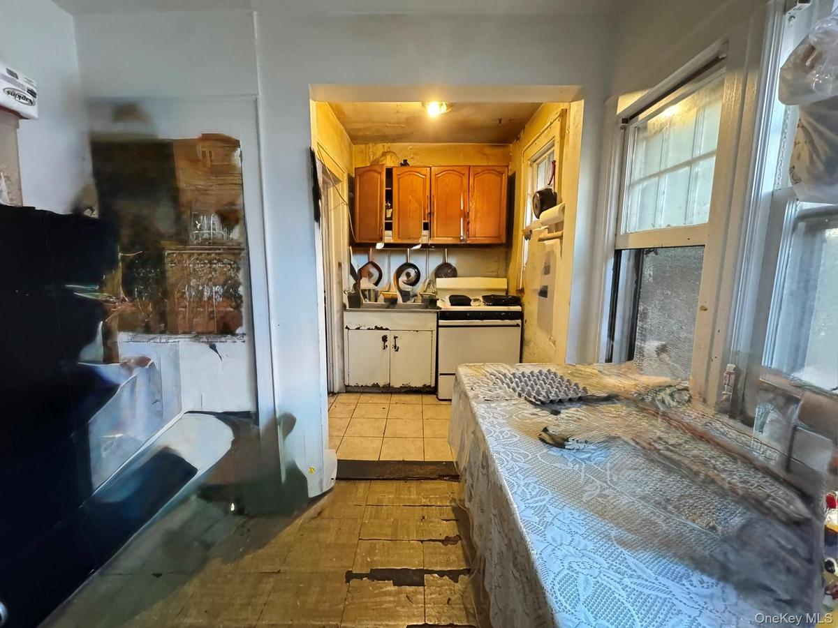 Kitchen with electric stove, brown cabinetry, light countertops, and light tile patterned floors
