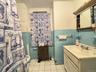 Full bathroom featuring light tile patterned floors, tile walls, vanity, wainscoting, and radiator